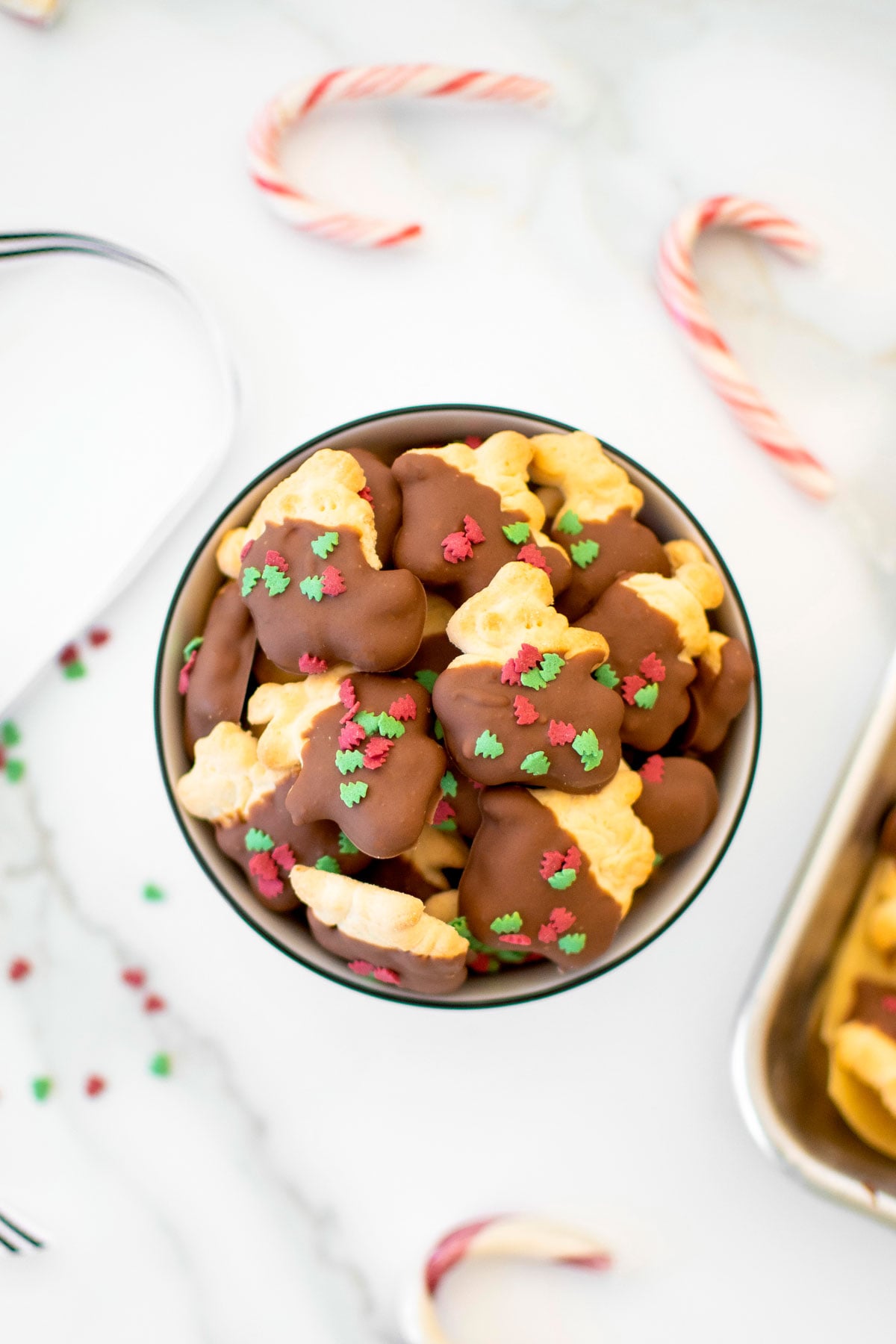 christmas chocolate dipped animal crackers in a bowl on a white marble counter.