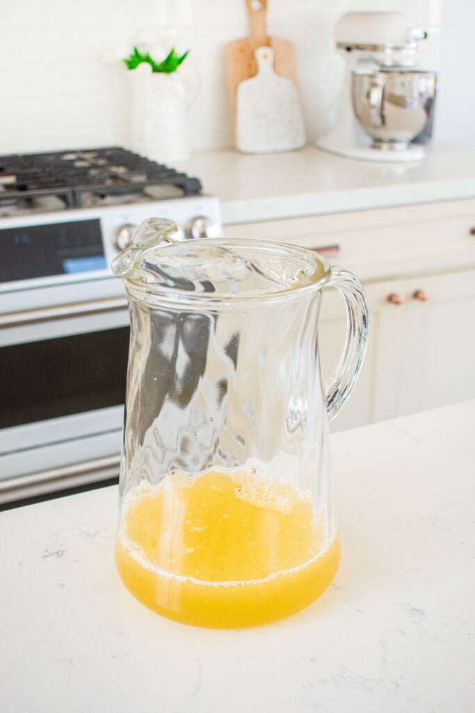 simple syrup and lemon juice in a glass pitcher on a kitchen countertop.