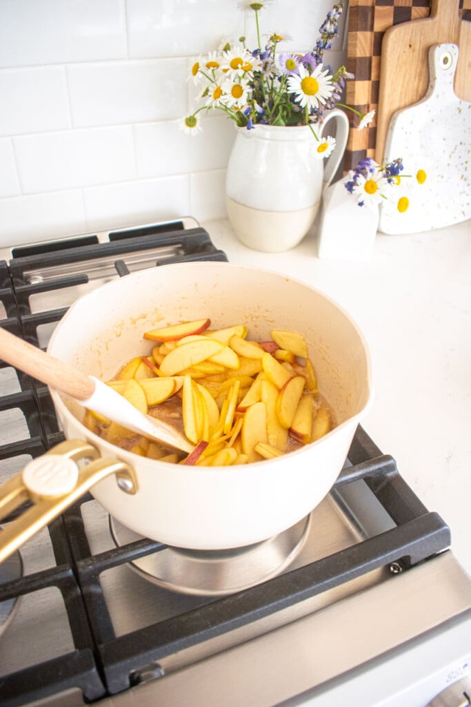 honey apple pie filling being cooked in a small pot on the stovetop.