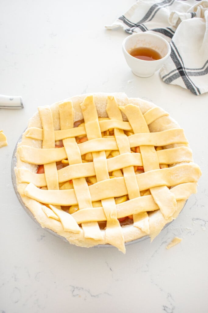 honey lemon apple pie with lattice pie dough woven on top on a marble counter.