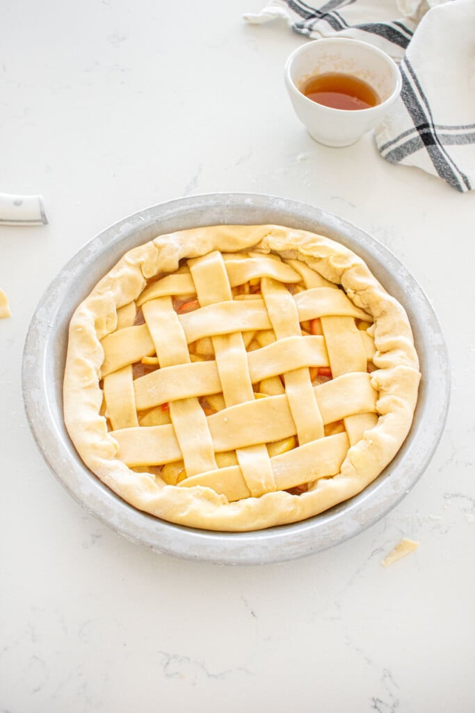 honey lemon apple pie with lattice pie dough and rolled in pie dough on a marble counter.