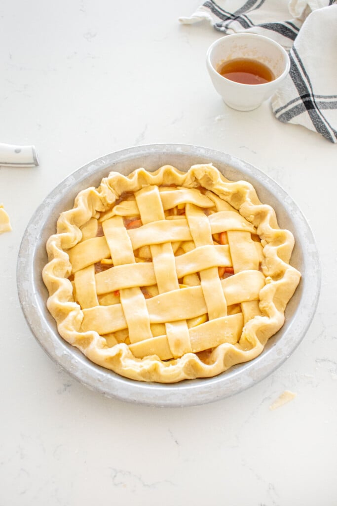 honey lemon apple pie with fluted pie dough on a marble counter.