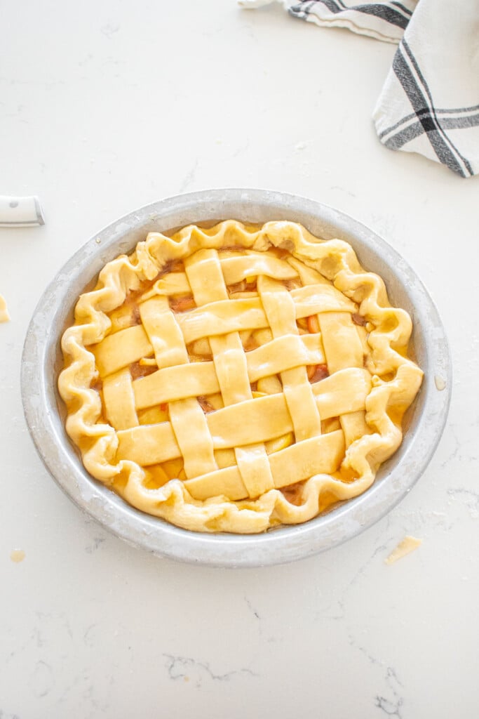 honey lemon apple pie with brushed on honey pie wash on a marble counter.
