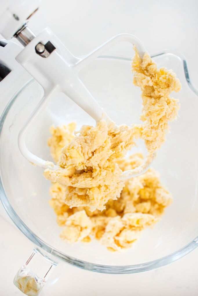shaggy pie dough in a glass mixing bowl on a marble counter.