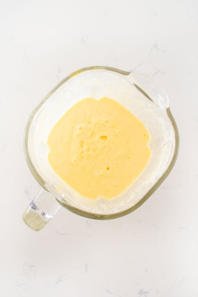 blender with orange creamsicle popsicle mixture in it on a white kitchen counter.