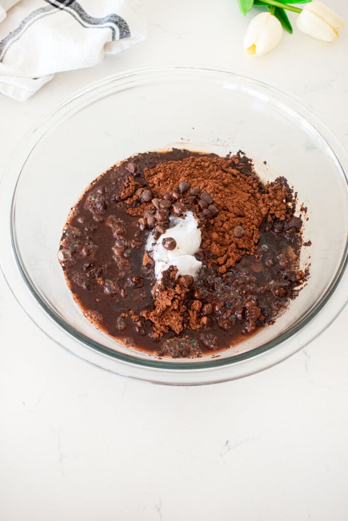 wet ingredients for vegan toasted coconut brownies in a glass mixing bowl on a white marble counter.