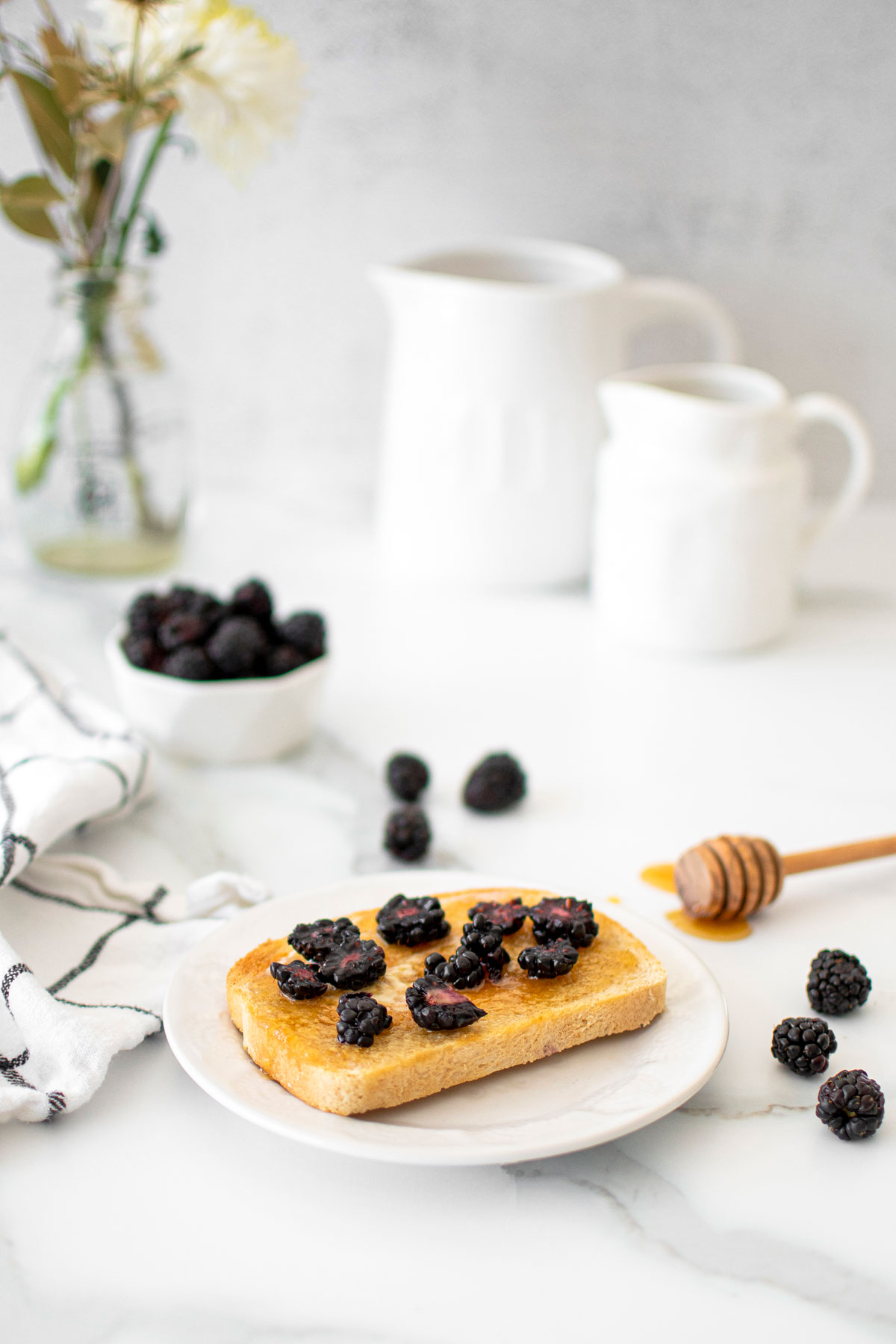 blackberry honey butter toast on a plate on a marble countertop.