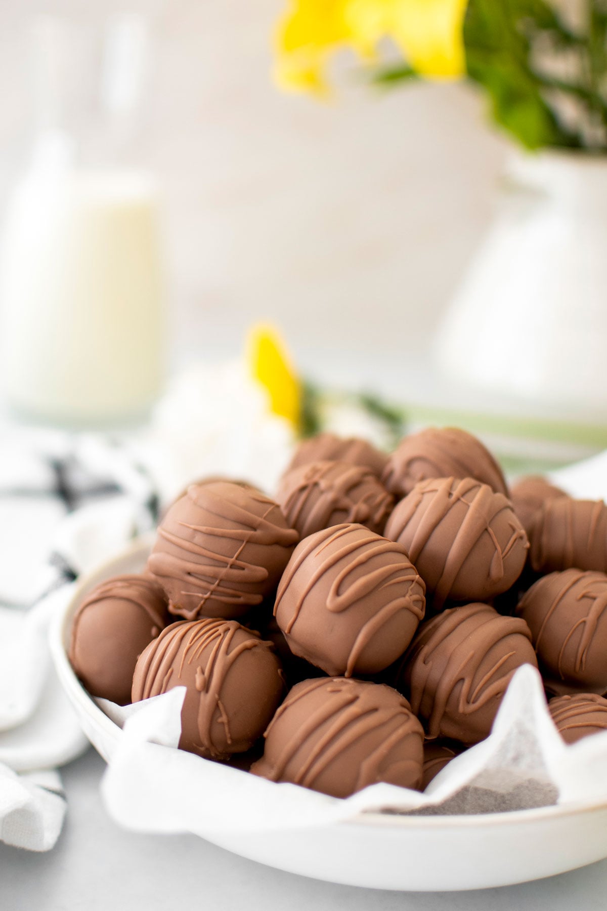 chocolate peanut butter cake balls in a bowl on a white table with fresh flowers.