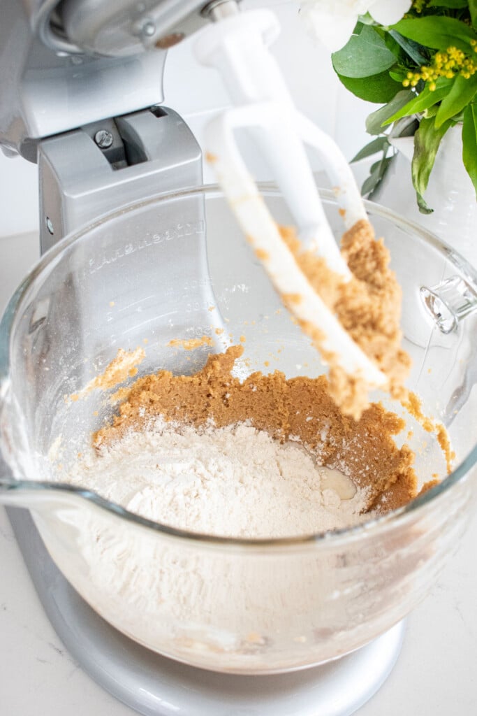 butter, sugar and flour in a mixing bowl being mixed together on the counter.