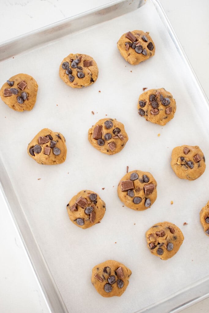 coffee creamer cookie dough balls on white parchment paper on a baking sheet.