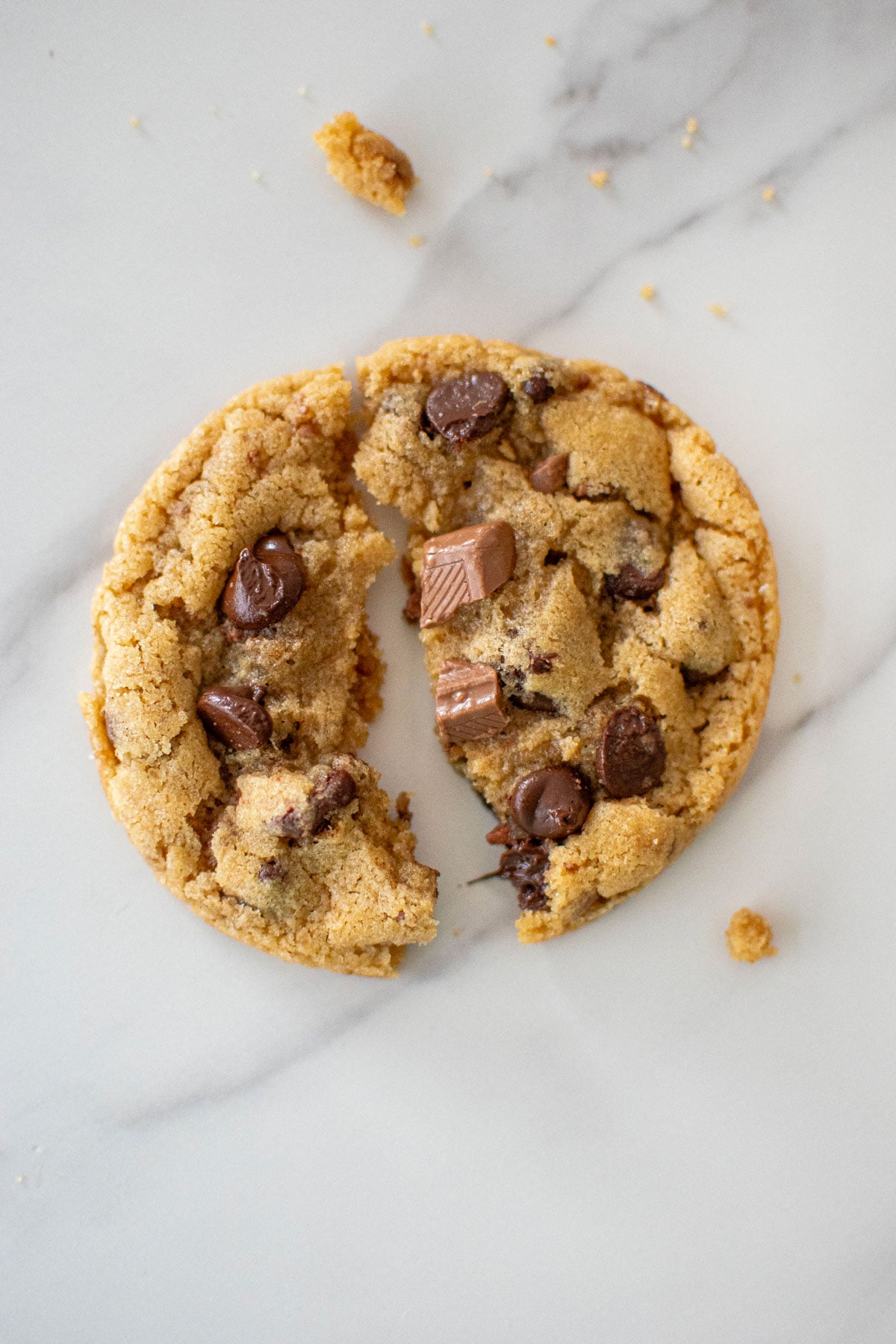 coffee creamer cookie broken in half on a white marble countertop.