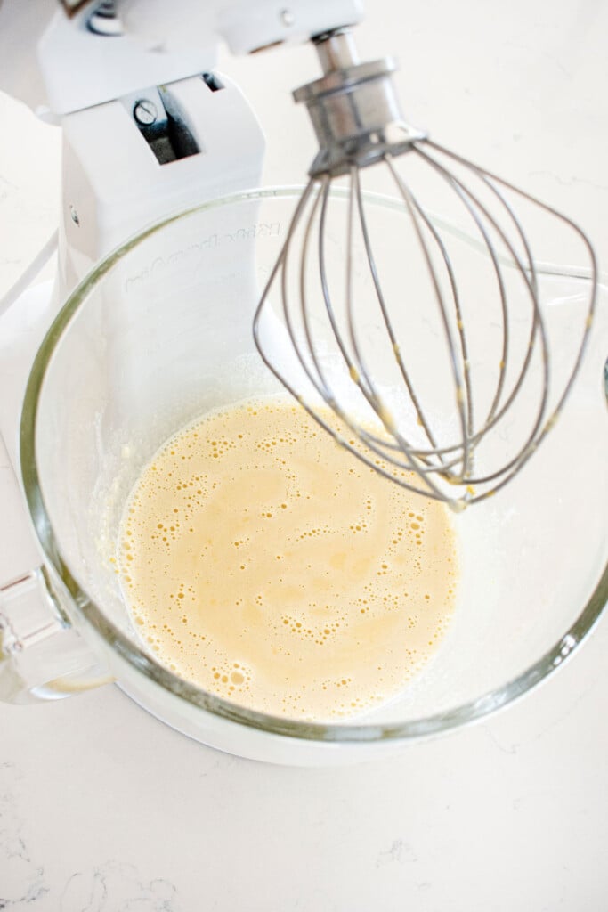 custard in a glass mixing bowl on a white marble counter.