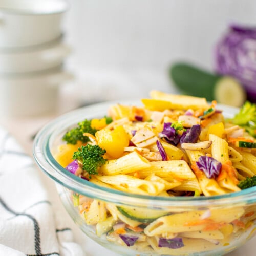 ranch pasta salad in a glass mixing bowl on a marble countertop.