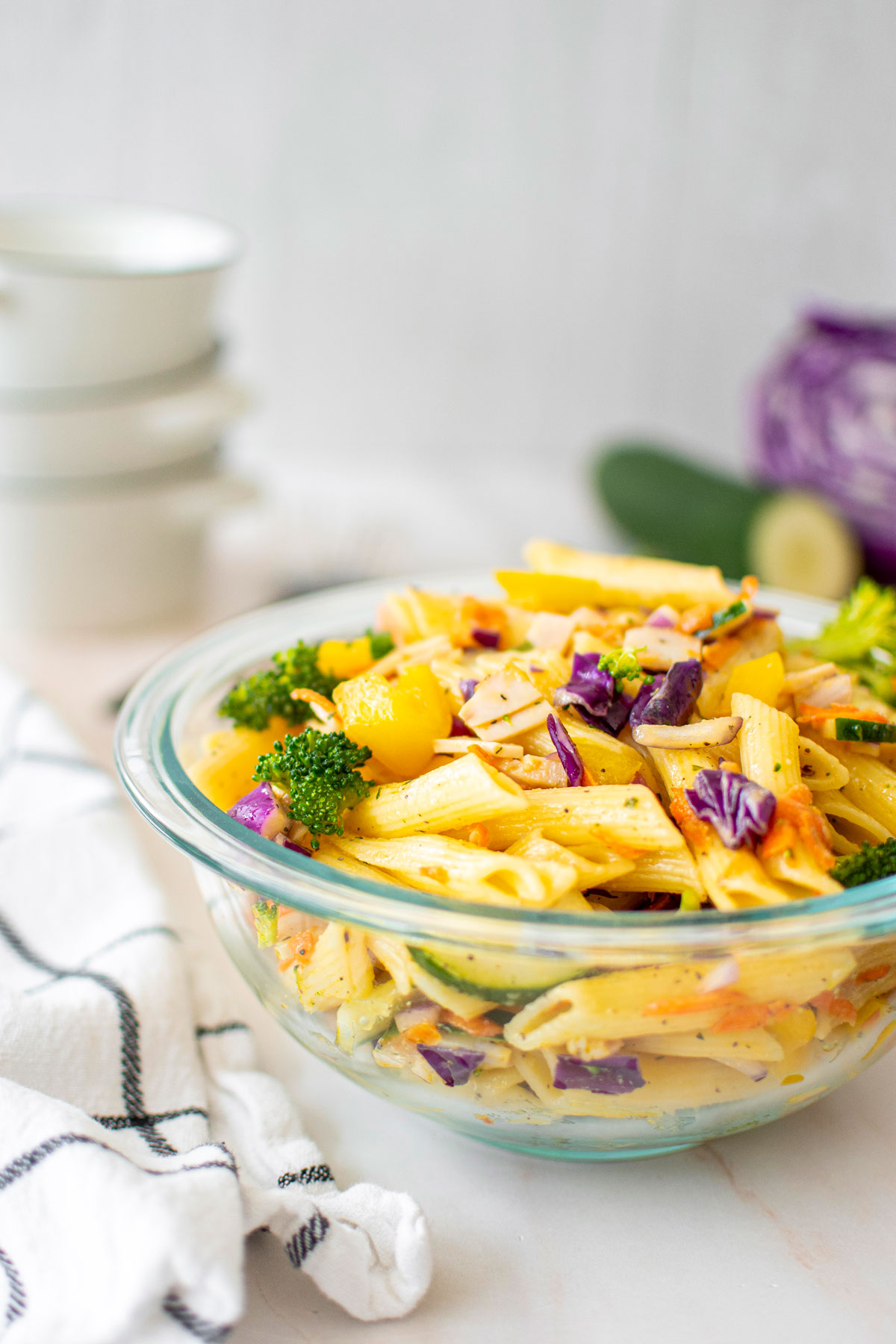 ranch pasta salad in a glass mixing bowl on a marble countertop.