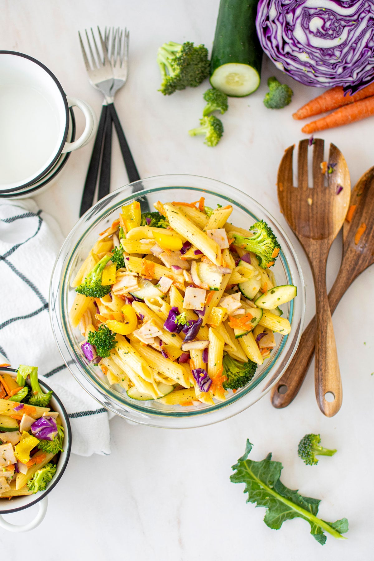 ranch pasta salad in a glass mixing bowl on a marble countertop.