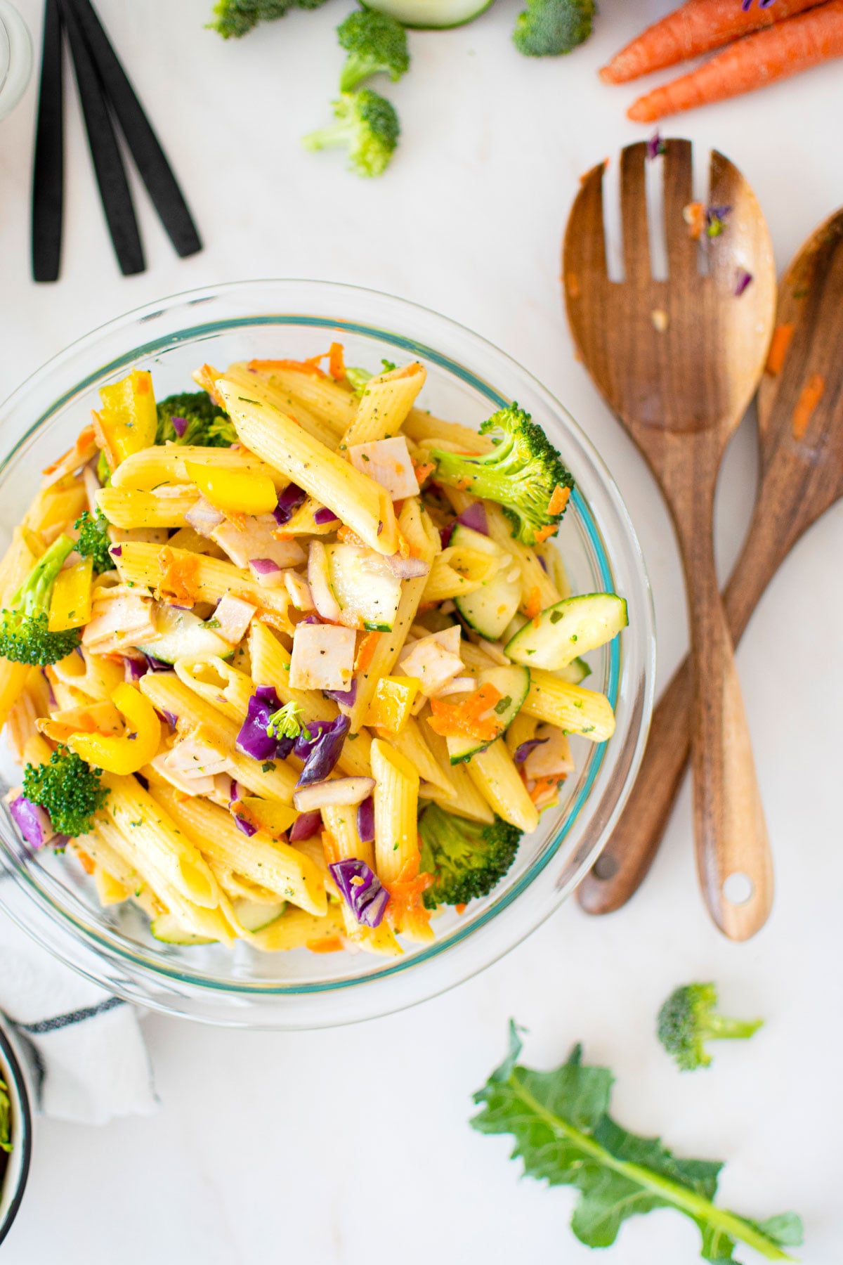 ranch pasta salad in a glass mixing bowl on a marble countertop.
