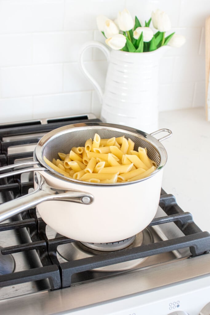 cooked pasta in a strainer in a pot on the stovetop.