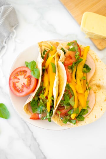 tomato basil soft tacos on a plate on a marble countertop.