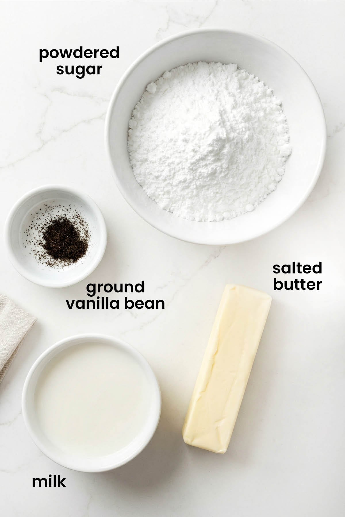 individual ingredients for vanilla bean buttercream frosting laid out against a white background.