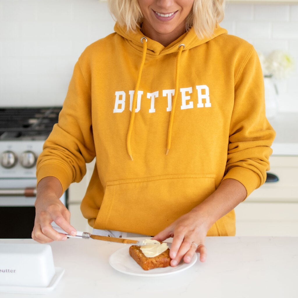 butter hooodie, girl wearing butter hoodie in kitchen spreading butter on banana bread