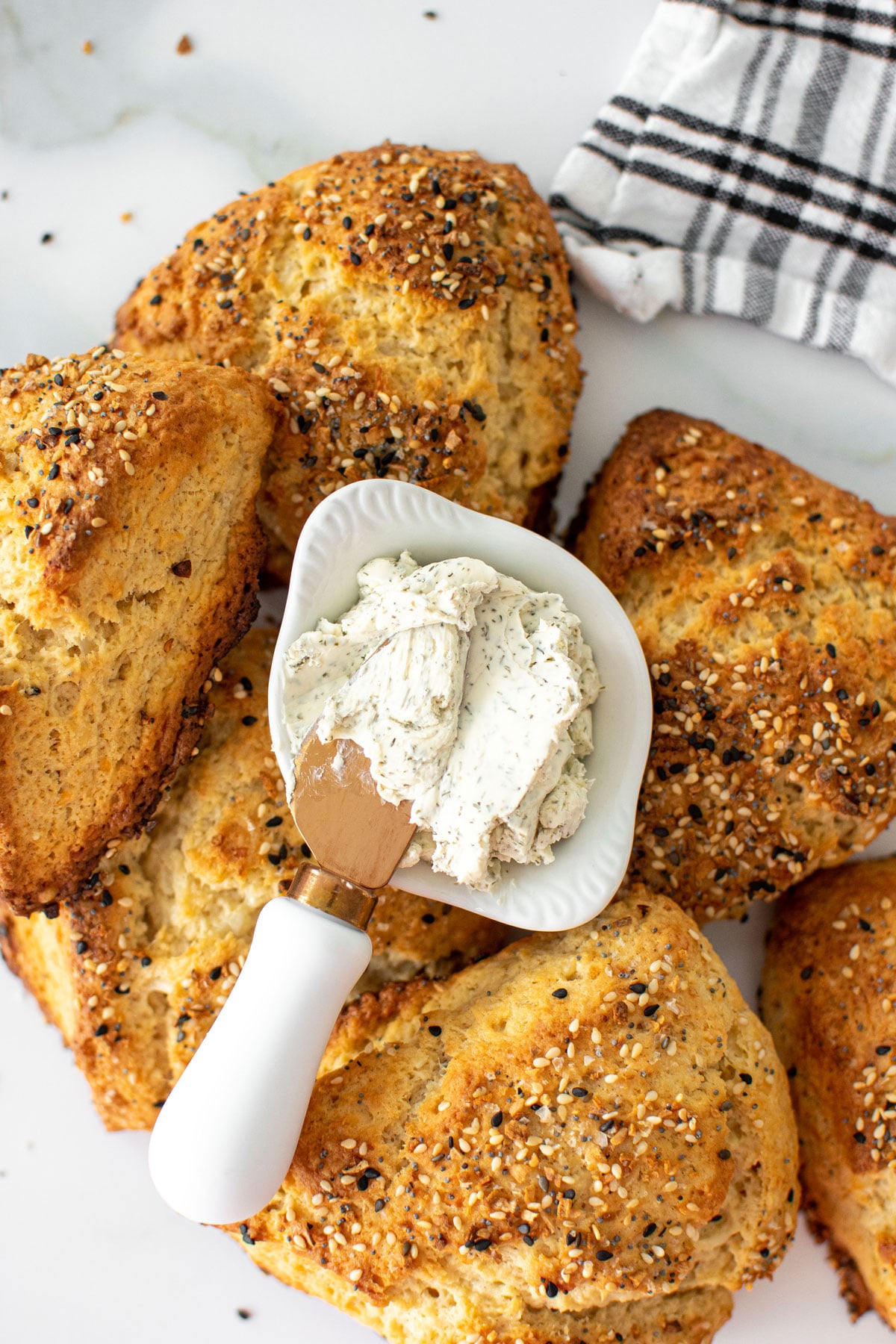 everything bagel scones with dill cream cheese spread on a white marble countertop.
