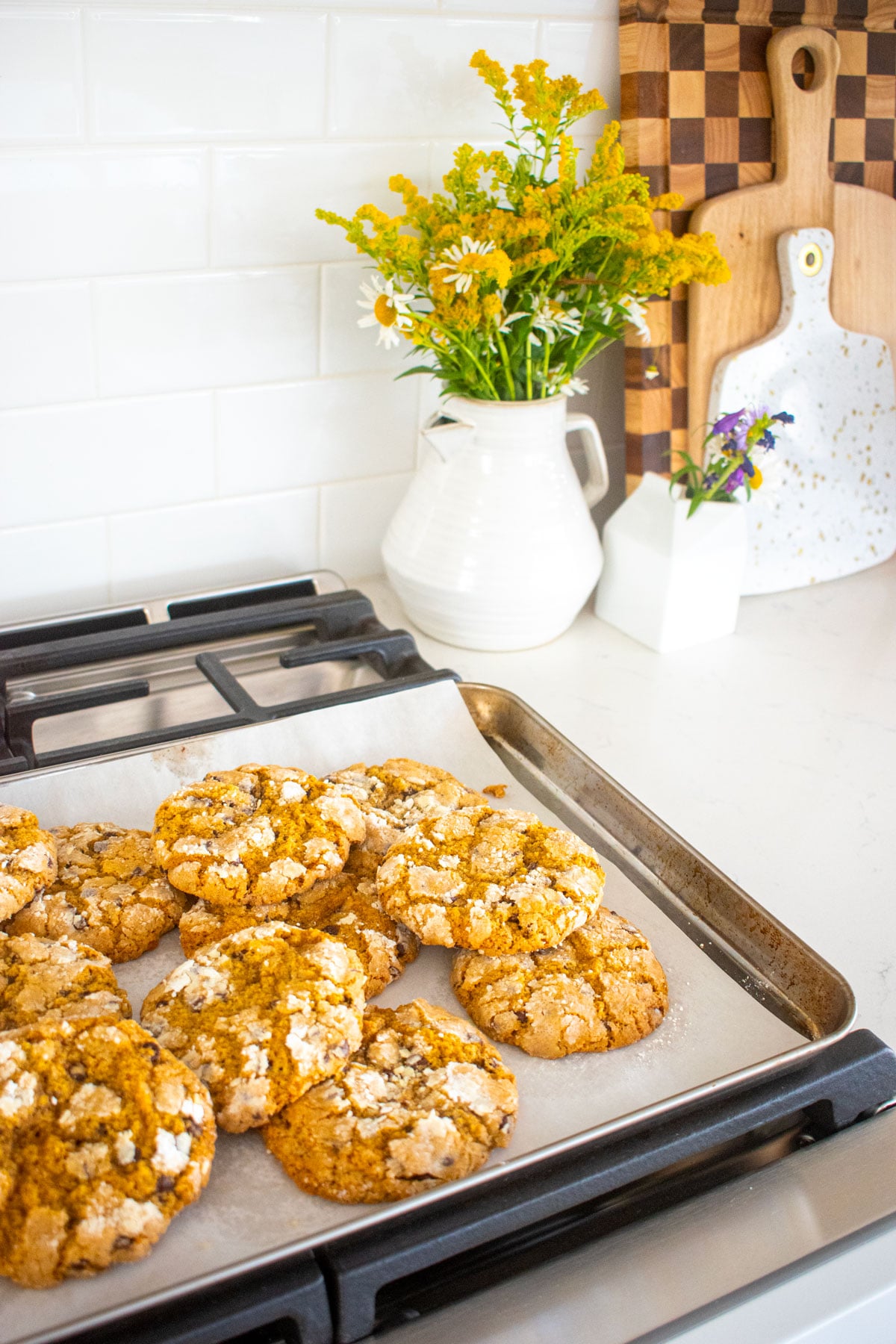 chocolate chip crinkle cookies on a baking sheet cooling on top of an oven.
