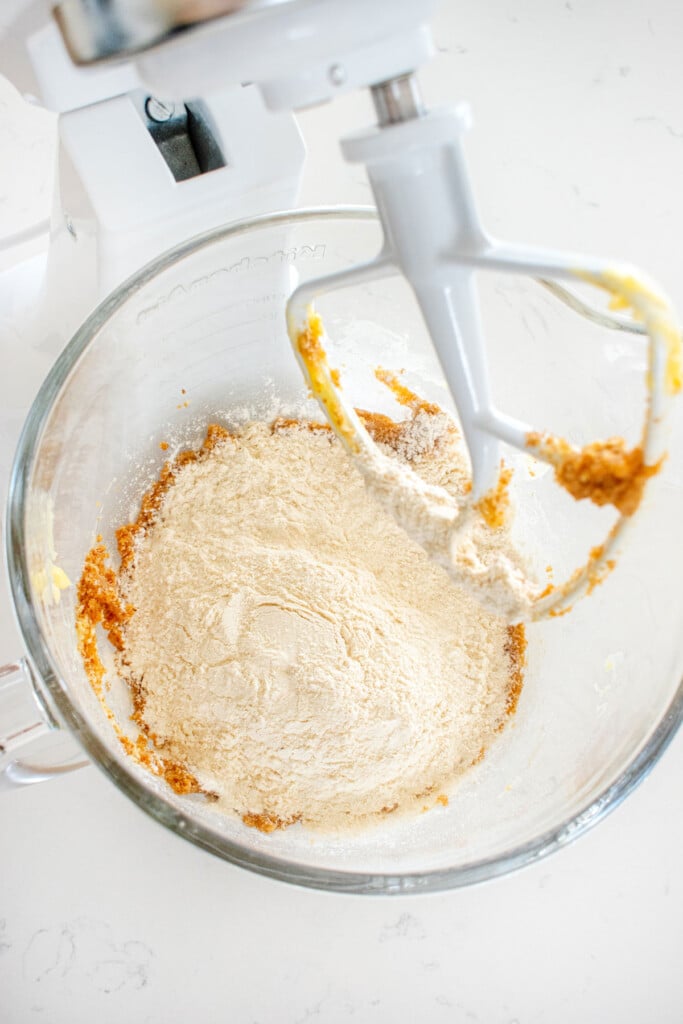 ingredients for chocolate chip crinkle cookies in a glass mixing bowl on a marble counter.