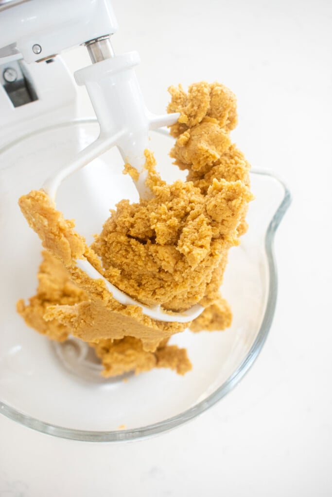 chocolate chip crinkle cookie dough in a glass mixing bowl on a marble counter.