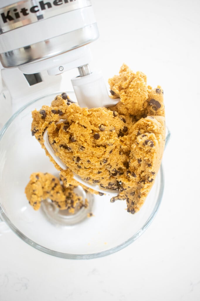 chocolate chip crinkle cookie dough in a glass mixing bowl on a marble counter.