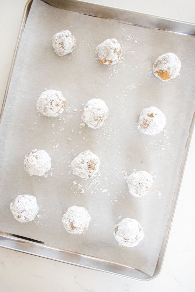 chocolate chip crinkle cookie dough balls on a baking sheet on a marble counter.