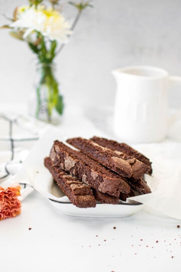 chocolate malt biscotti in a white serving platter on a white marble counter.