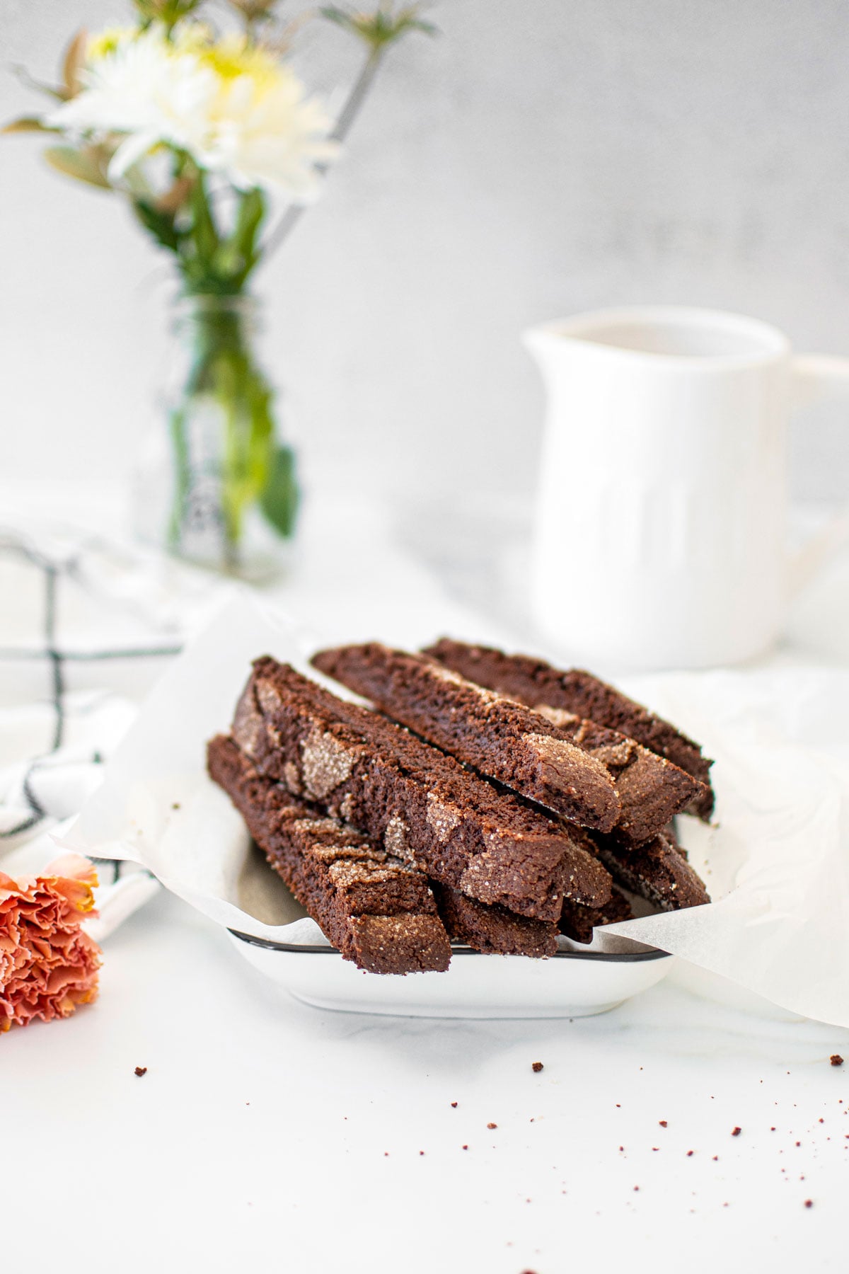 chocolate malt biscotti in a white serving platter on a white marble counter.
