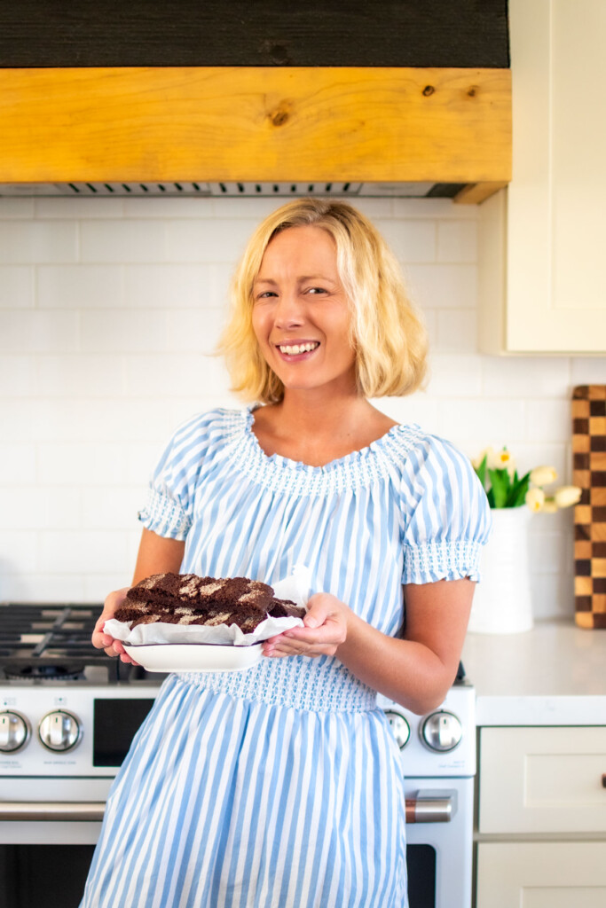woman holding a platter of chocolate malt biscotti in the kitchen.