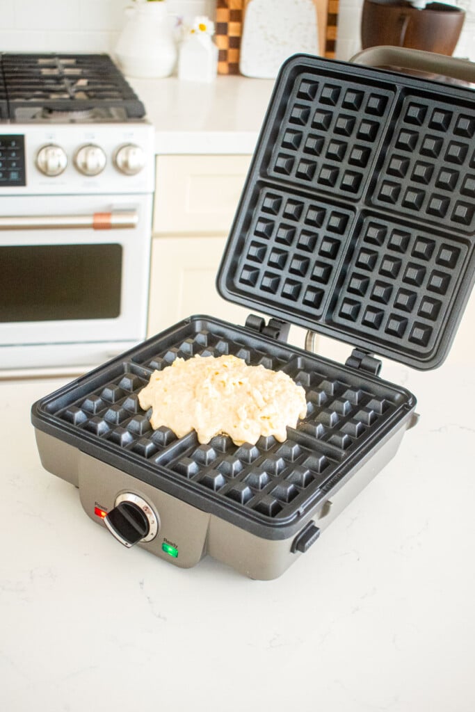 waffle iron on a marble counter with eggless banana waffle batter in the center.
