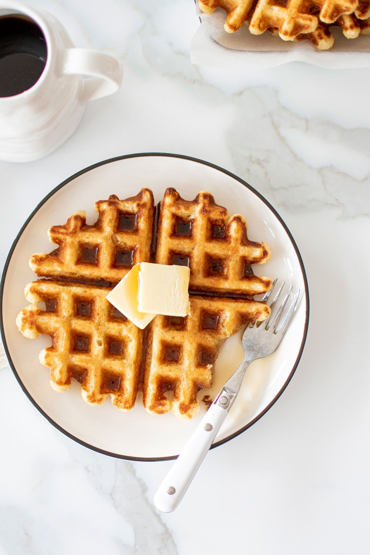 eggless banana waffles on a plate with butter and a fork.