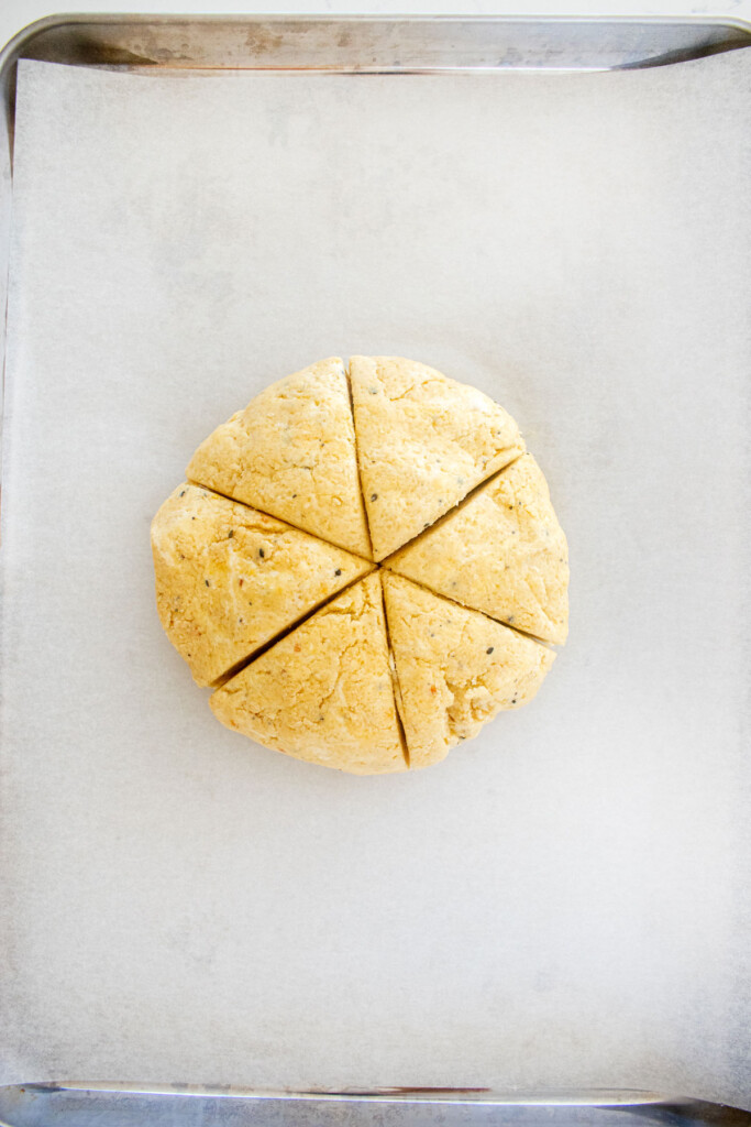 everything bagel scones dough on a baking sheet cut into 6 triangle slices.