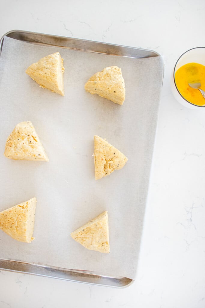everything bagel scones cut into triangles on a baking sheet.