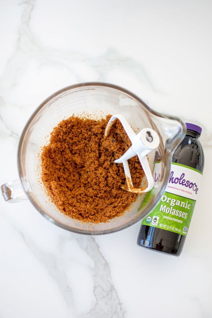 light brown sugar in a glass mixing bowl on a white marble counter.