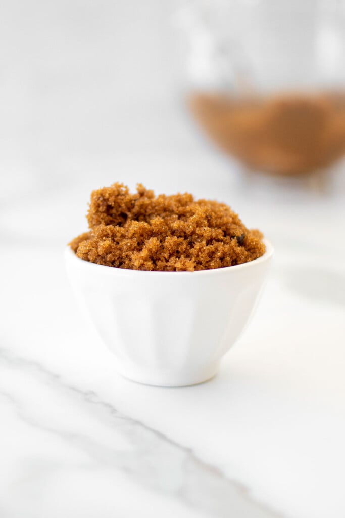 homemade light brown sugar in a small white bowl on a marble counter.