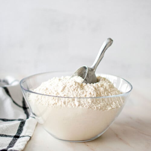 glass bowl of homemade organic cake flour with a scoop in it.