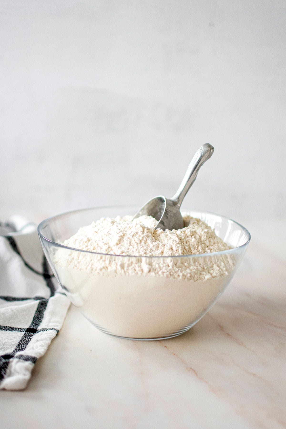 glass bowl of homemade organic cake flour with a scoop in it.