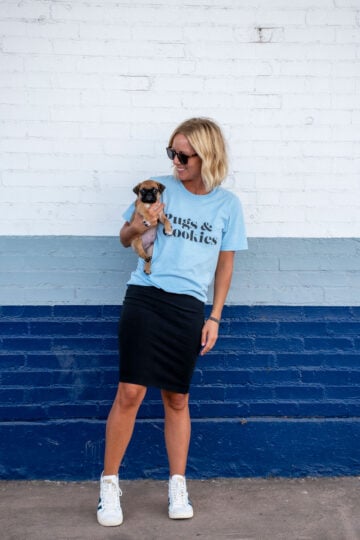 girl wearing pugs and cookies tee shirt holding a pug puppy