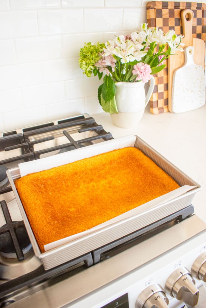 9x13 inch baked white cake cooling on top of an oven.