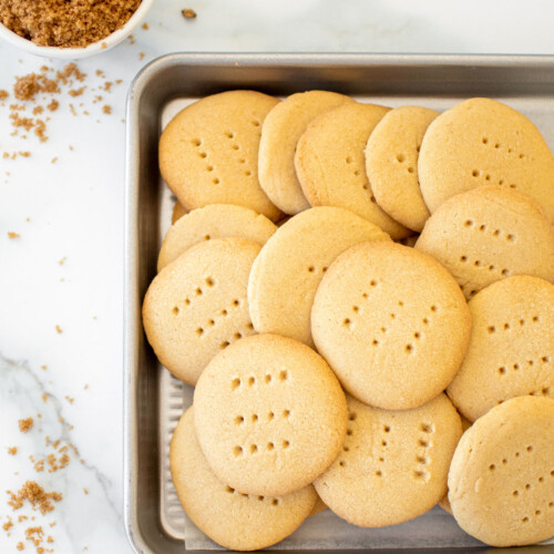 brown sugar shortbread cookies on a baking sheet on a white marble counter.