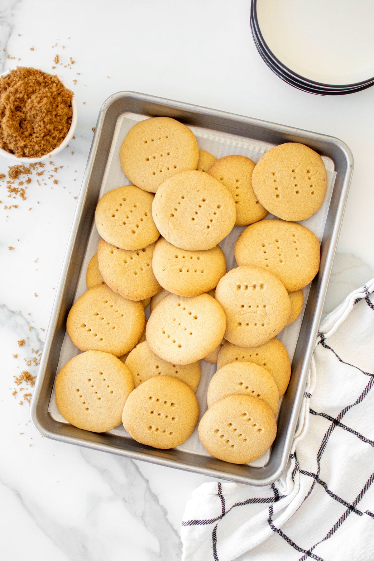 brown sugar shortbread cookies on a baking sheet on a white marble counter.