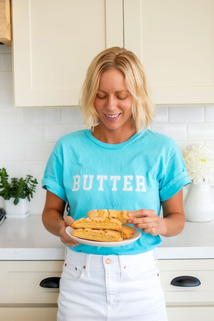 woman wearing a butter tee shirt holding a plate of kamut flour biscotti.