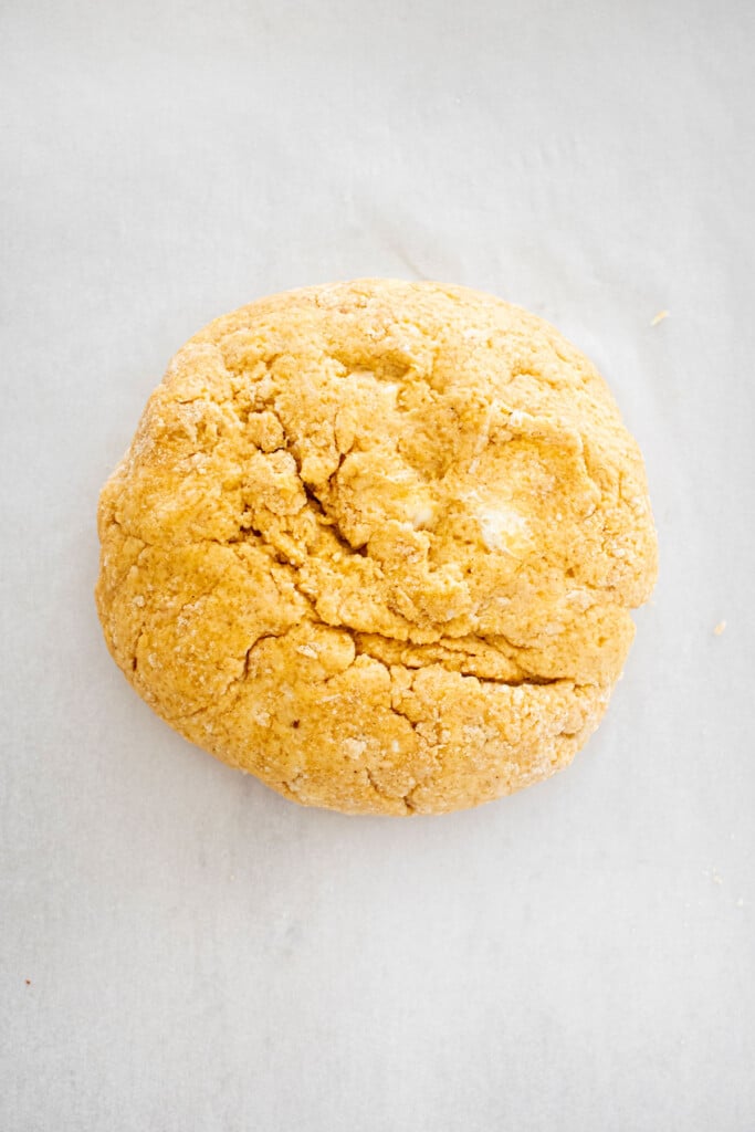 eggless pumpkin spice scone dough formed into a round disk on a baking sheet.