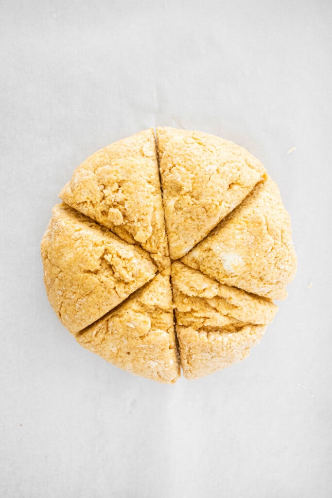 eggless pumpkin spice scone dough cut into triangles on a baking sheet.