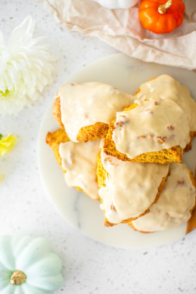 eggless pumpkin spice scones on a marble serving board with pumpkins and fresh flowers.