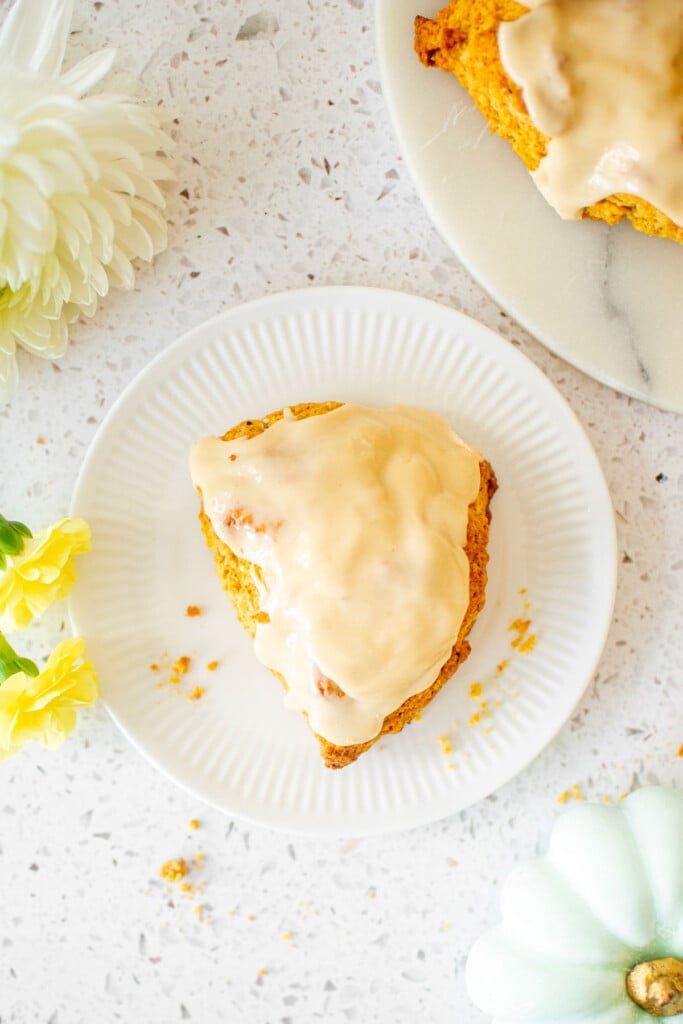 eggless pumpkin spice scone on a plate on a white stone counter with pumpkins.